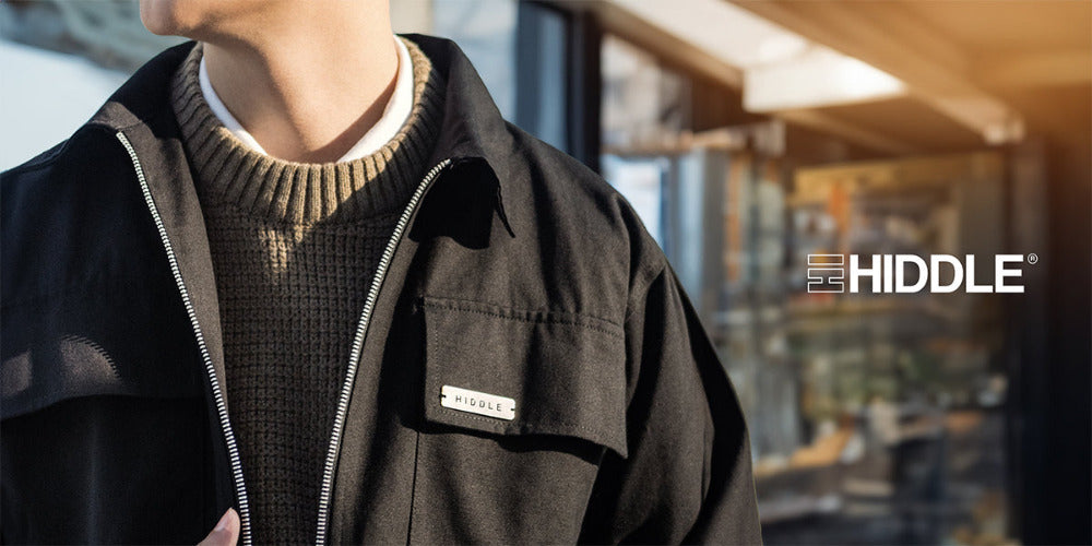 Person wearing a black jacket with 'Hiddle' branding in an indoor setting.