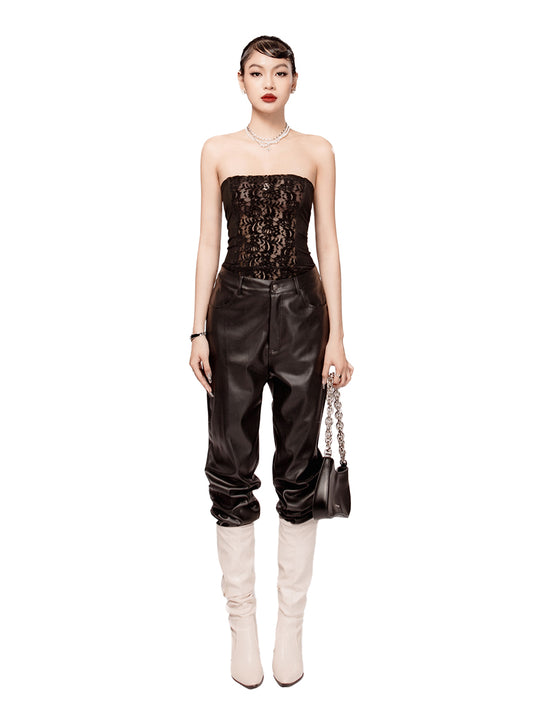 Woman wearing a black strapless top and leather pants with white boots on a white background