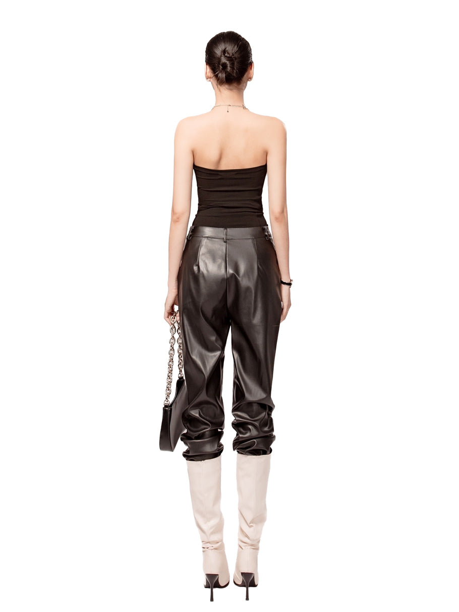 Woman wearing a strapless top and leather pants on a white background