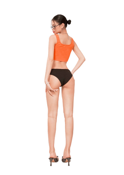 Woman wearing an orange top and black bottoms on a white background