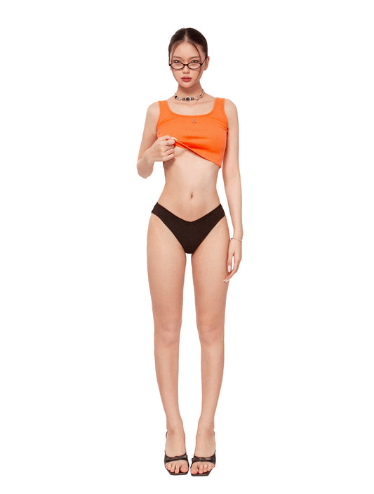 Woman wearing an orange top and black bottoms on a white background