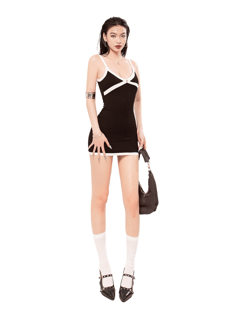 Woman wearing a black and white dress with a bow, holding a brown handbag on a white background