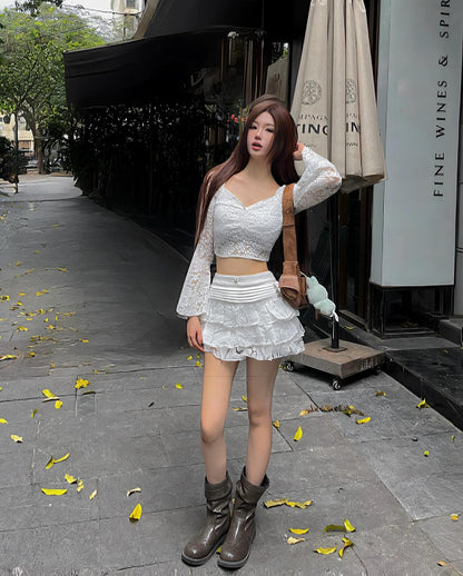 Woman in a white outfit standing on a sidewalk with a building in the background