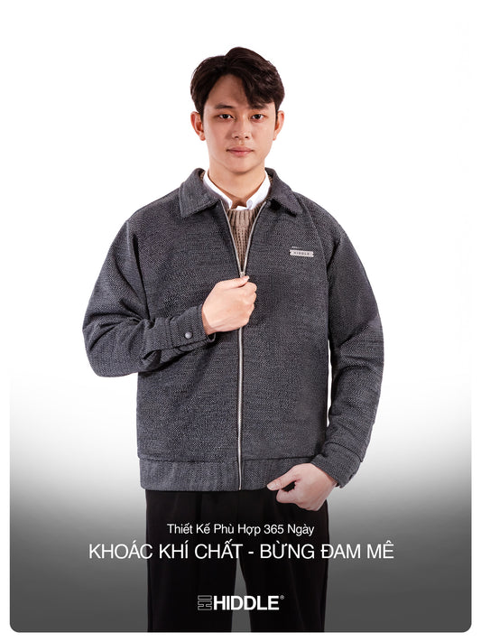 Man wearing a gray jacket with a visible brand logo on a white background