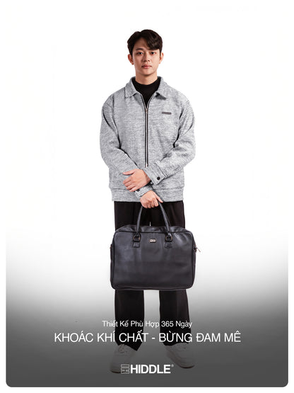 Man holding a black bag with a gray jacket on a white background