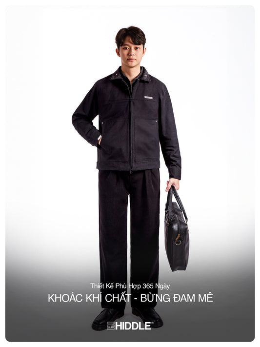 Person wearing a black work uniform holding a tool bag on a white background