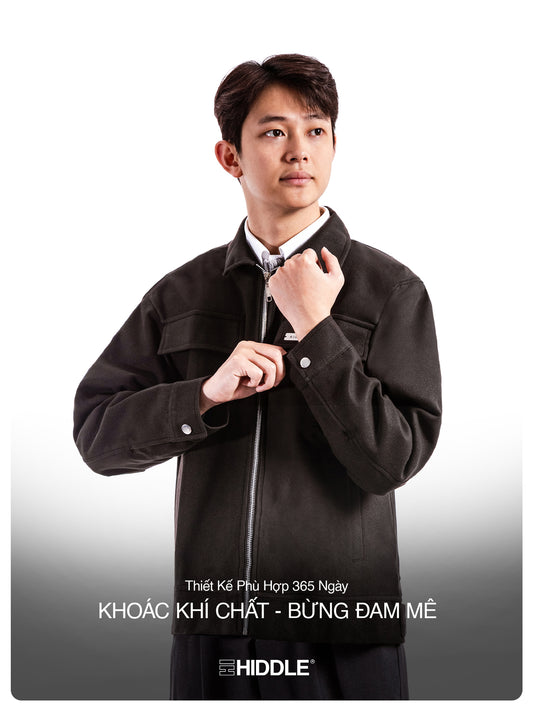 Man adjusting his collar in a black jacket with Hiddle branding