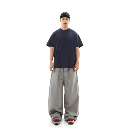 Person wearing a navy t-shirt and gray pants on a white background