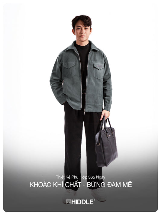 Man wearing a gray jacket holding a bag on a white background with Hiddle branding.