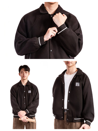 Black varsity jacket with white trim worn by a person on a white background