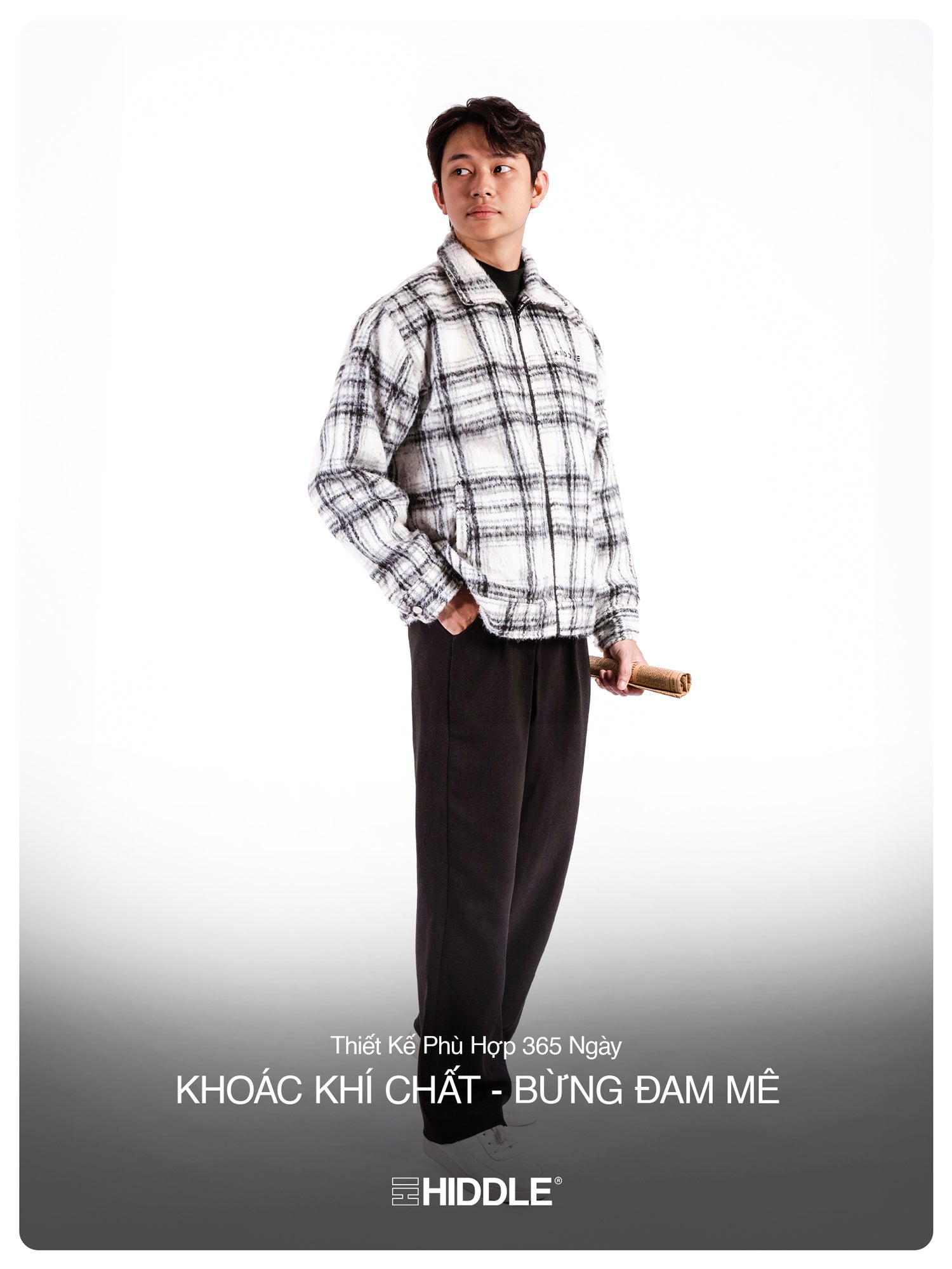 Person wearing a checkered shirt and dark pants with a product in hand on a white background, featuring the Hiddle brand.