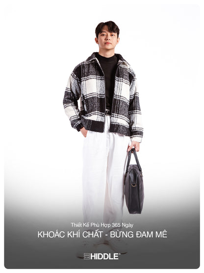 Person wearing a black and white checkered jacket with a gray bag on a white background