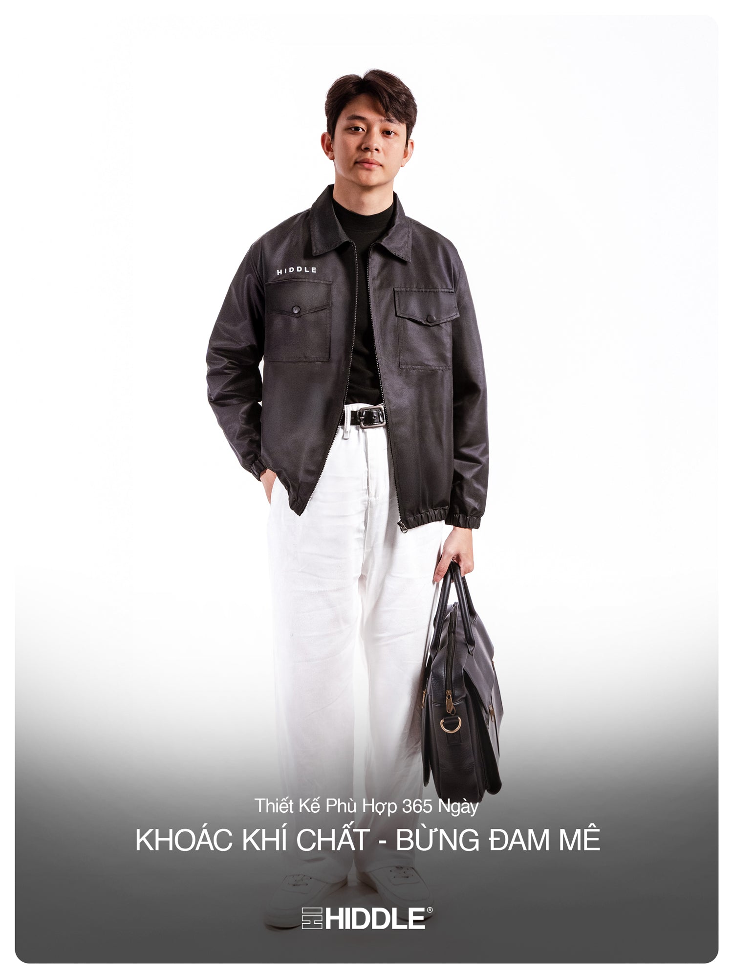 Man wearing a black jacket with visible branding, holding a bag on a white background