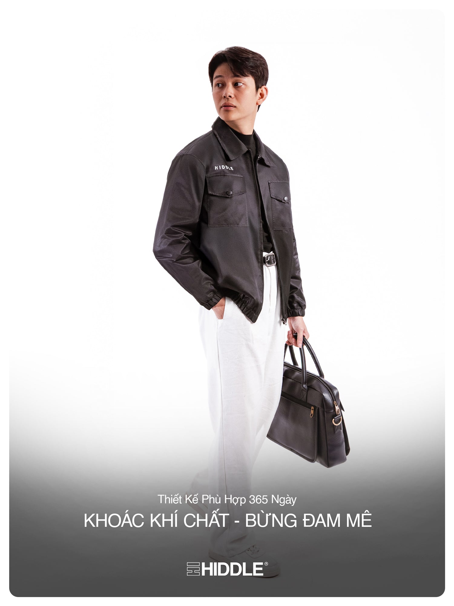 Person wearing a dark jacket holding a bag with Hiddle branding on a white background