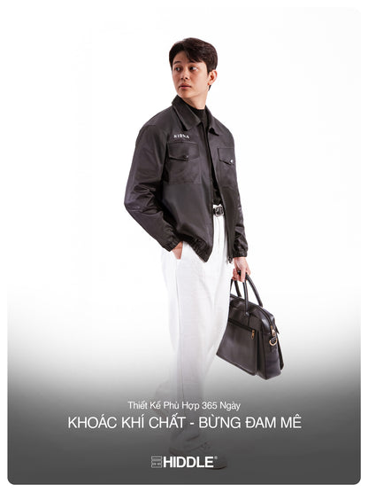 Person wearing a dark jacket holding a bag with Hiddle branding on a white background