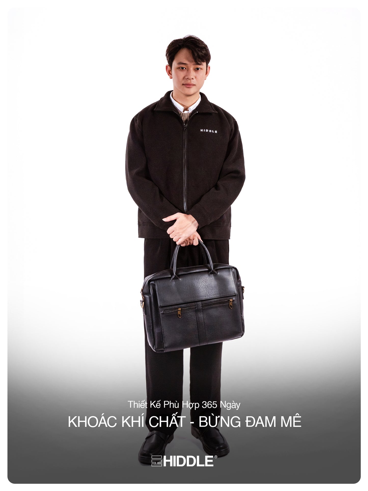 Man holding a black briefcase wearing a black jacket with a visible brand logo on a white background.