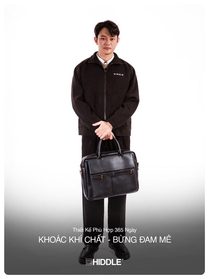 Man holding a black briefcase wearing a black jacket with a visible brand logo on a white background.