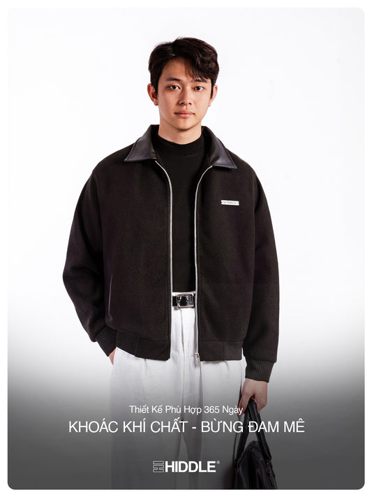 Man wearing a black jacket with a visible brand logo on a white background