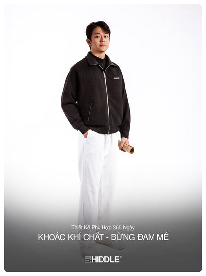 Man wearing a black jacket with a visible brand logo on a white background