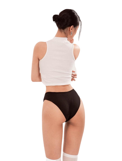 Woman wearing a white sleeveless top and black high-waisted underwear on a white background
