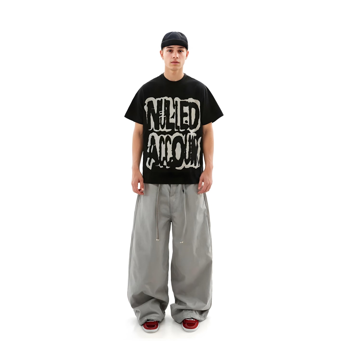 Person wearing a black t-shirt with graphic design and gray pants on a white background
