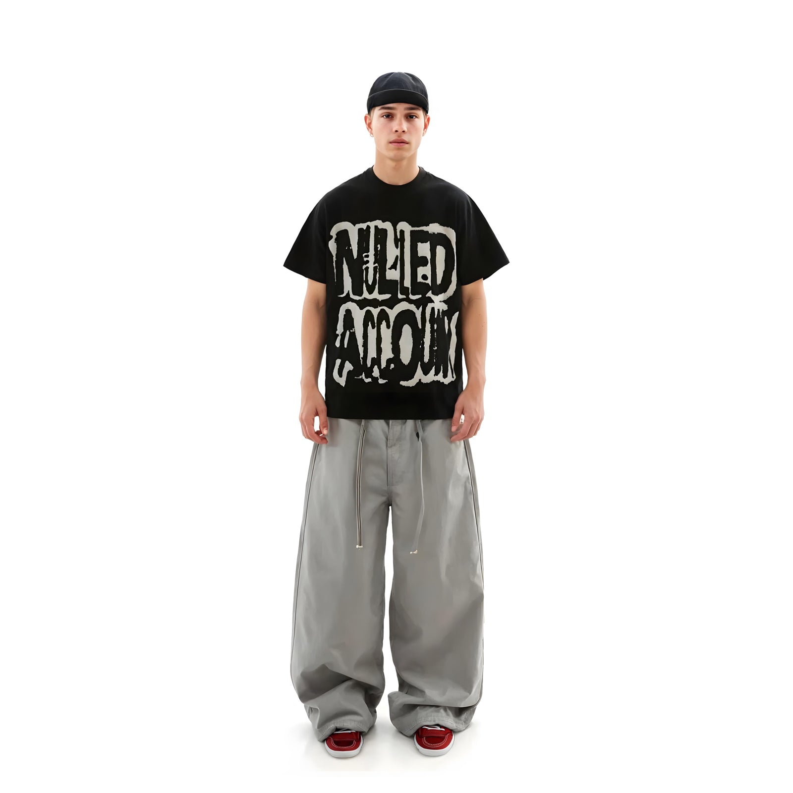 Person wearing a black t-shirt with graphic design and gray pants on a white background
