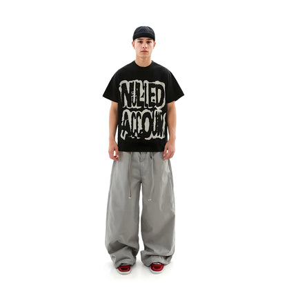 Person wearing a black t-shirt with graphic design and gray pants on a white background