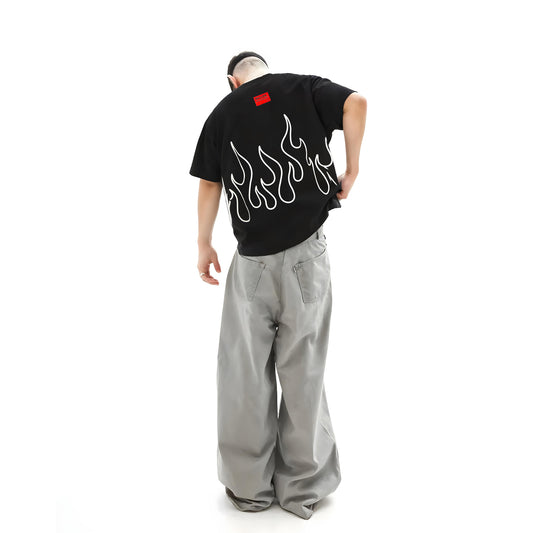 Person wearing a black t-shirt with white flame design and gray pants on a white background