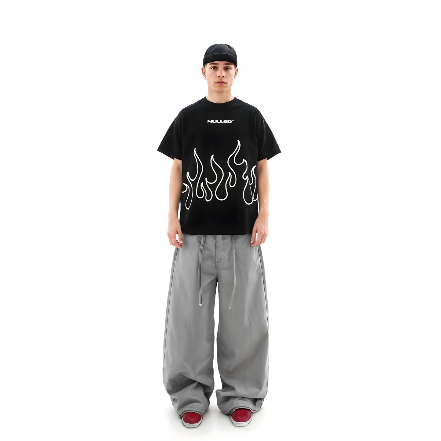 Person wearing a black t-shirt with flame design and gray pants on a white background