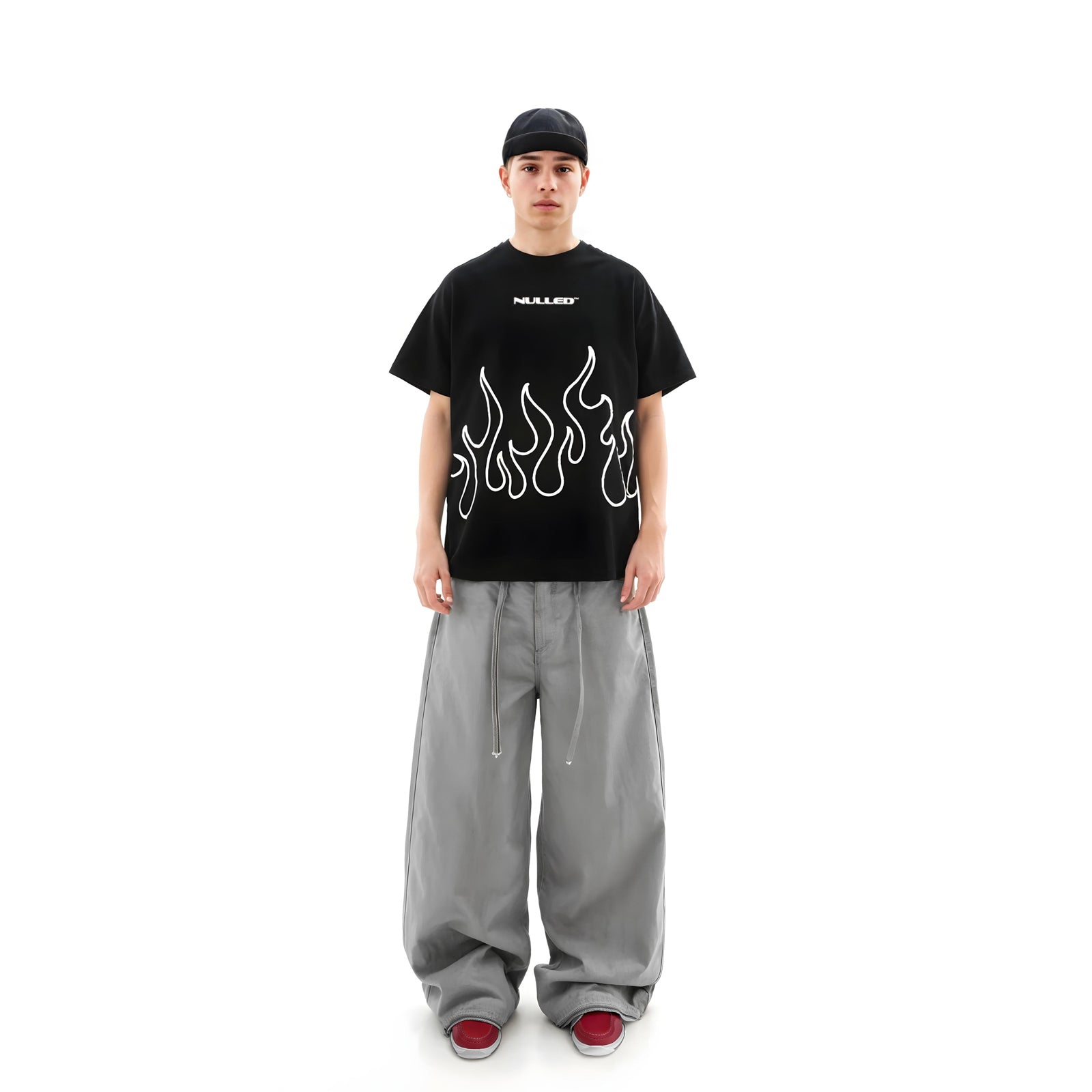 Person wearing a black t-shirt with flame design and gray pants on a white background