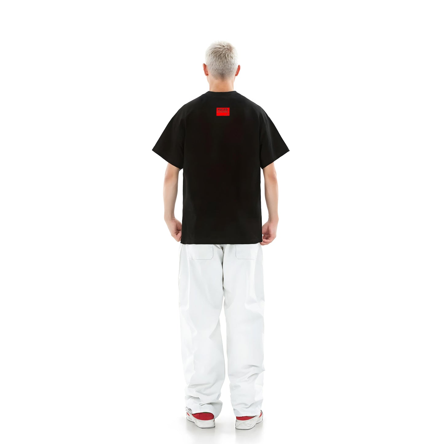 Person wearing a black t-shirt with a red logo on the back, standing against a white background