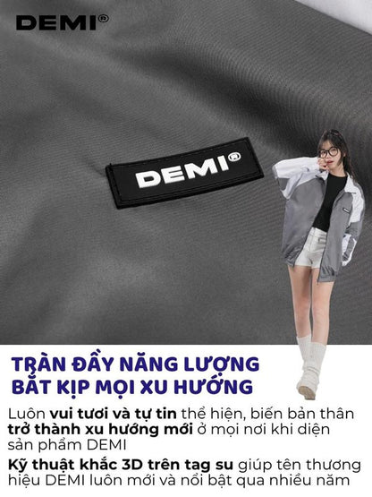 Person wearing a gray jacket with DEMI branding on a dark fabric background