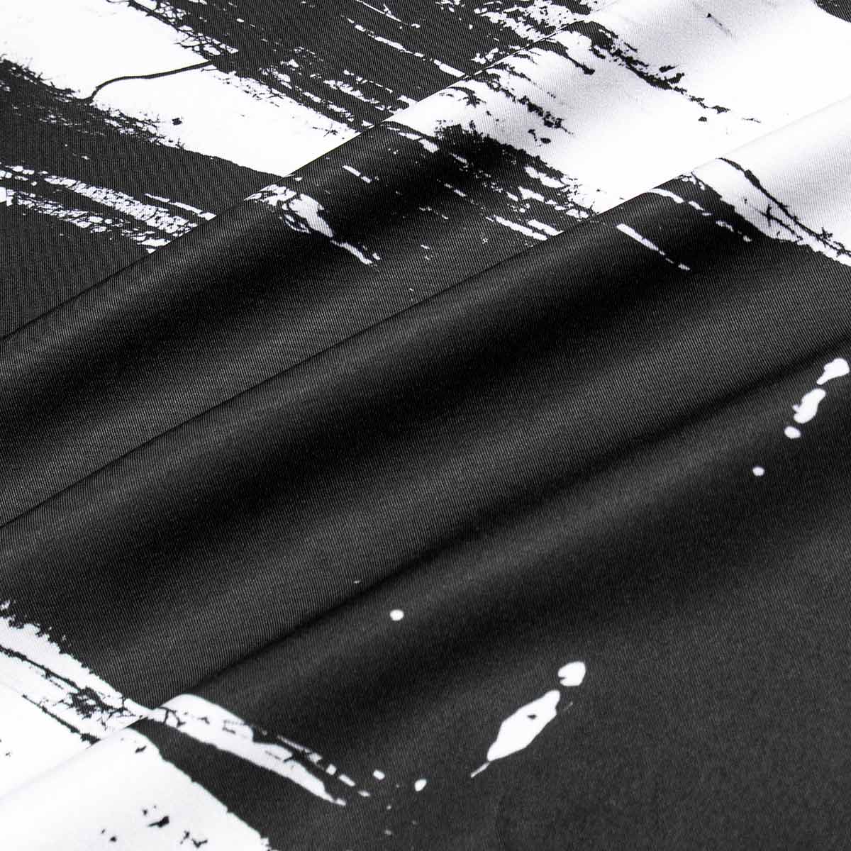 Close-up of black fabric with white paint splashes on a textured background