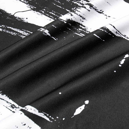 Close-up of black fabric with white paint splashes on a textured background