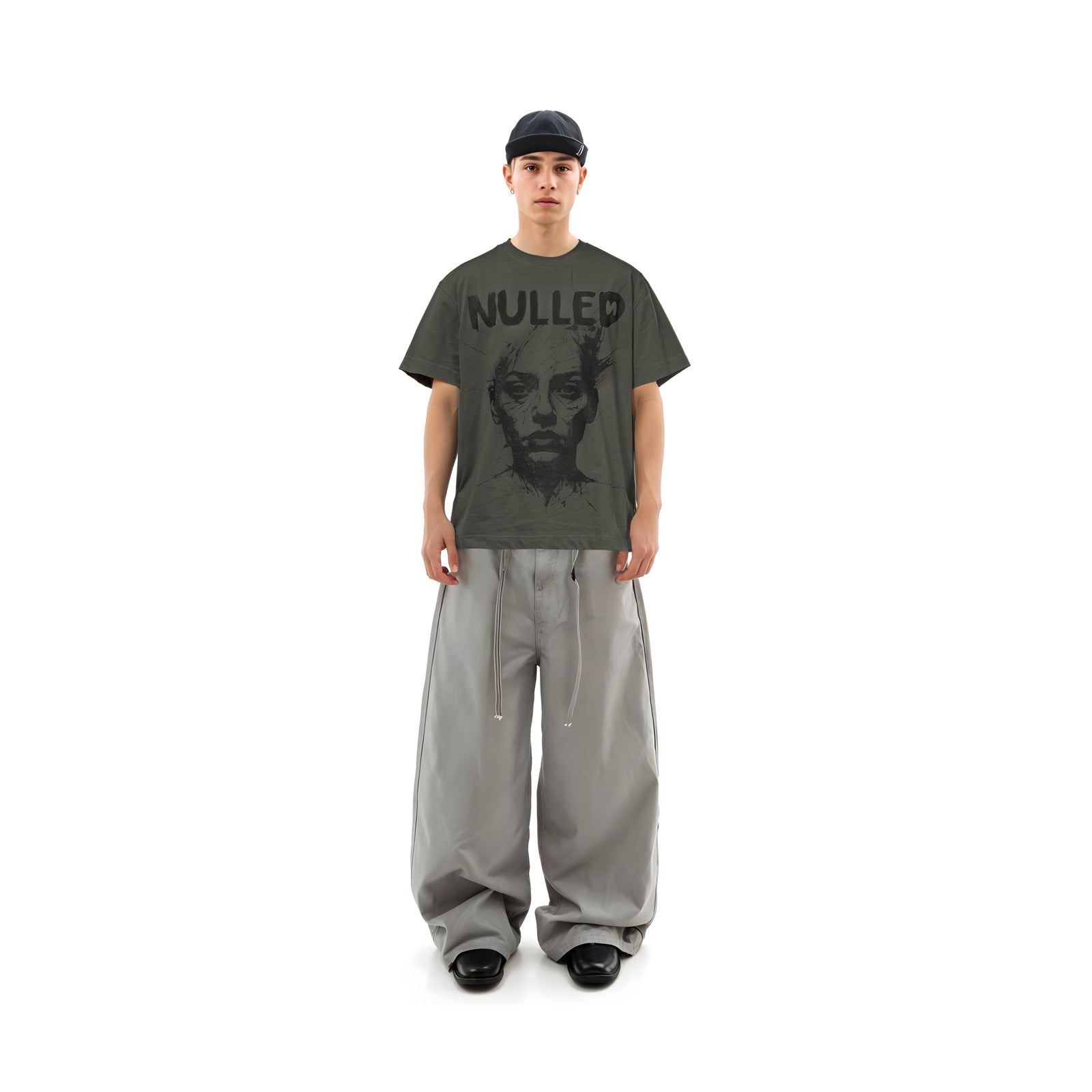 Person wearing a dark gray t-shirt with 'NULLED' text and a graphic design, paired with light gray pants on a white background.