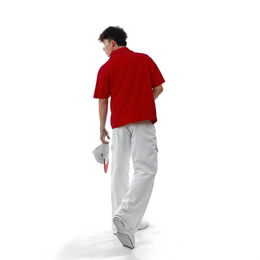 Person wearing a red polo shirt and gray pants on a white background