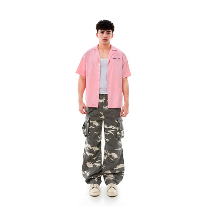 Person wearing a pink shirt and camouflage pants on a white background