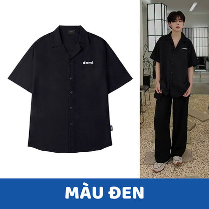 Black shirt with 'demi' logo on a white background, worn by a person indoors.