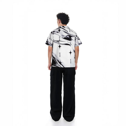 Person wearing a black and white patterned shirt with black pants on a white background