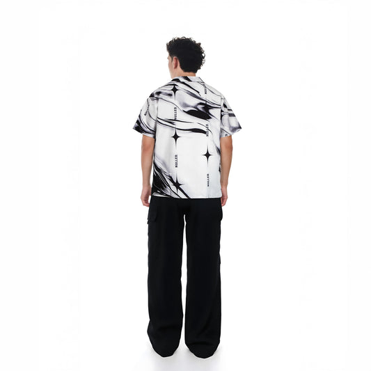 Person wearing a black and white patterned shirt with black pants on a white background