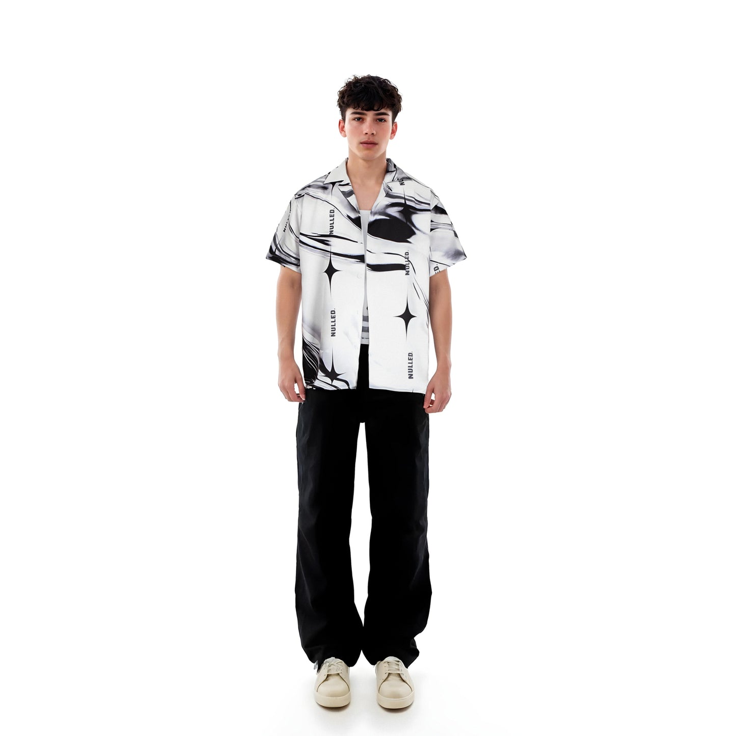 Person wearing a black and white patterned shirt with black pants on a white background