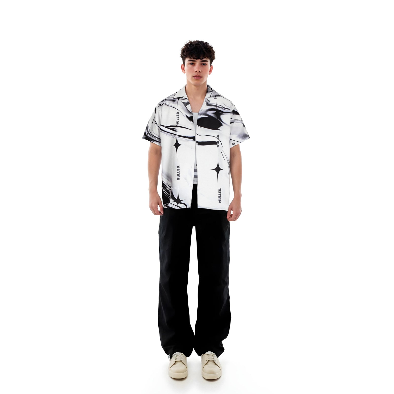 Person wearing a black and white patterned shirt with black pants on a white background