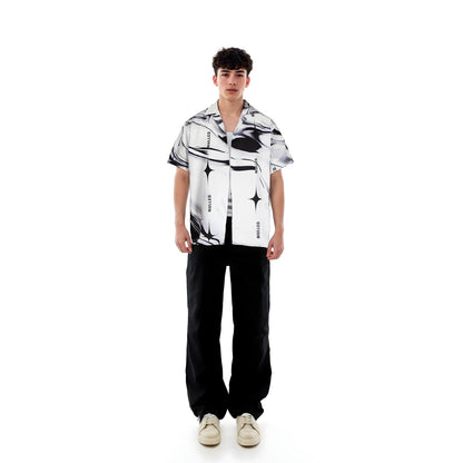 Person wearing a black and white patterned shirt with black pants on a white background