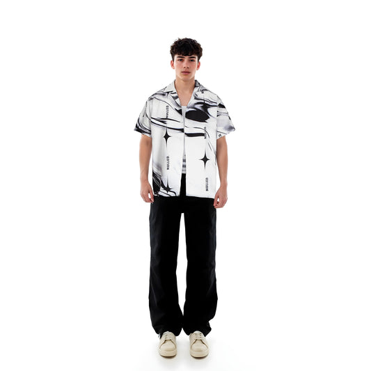 Person wearing a black and white patterned shirt with black pants on a white background
