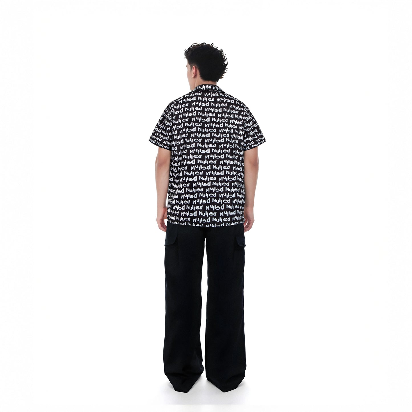 Person wearing a black and white patterned shirt with wide-leg pants on a white background