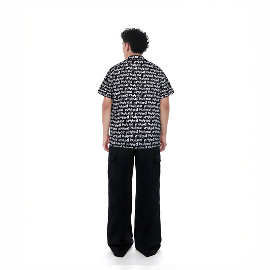 Person wearing a black and white patterned shirt with wide-leg pants on a white background