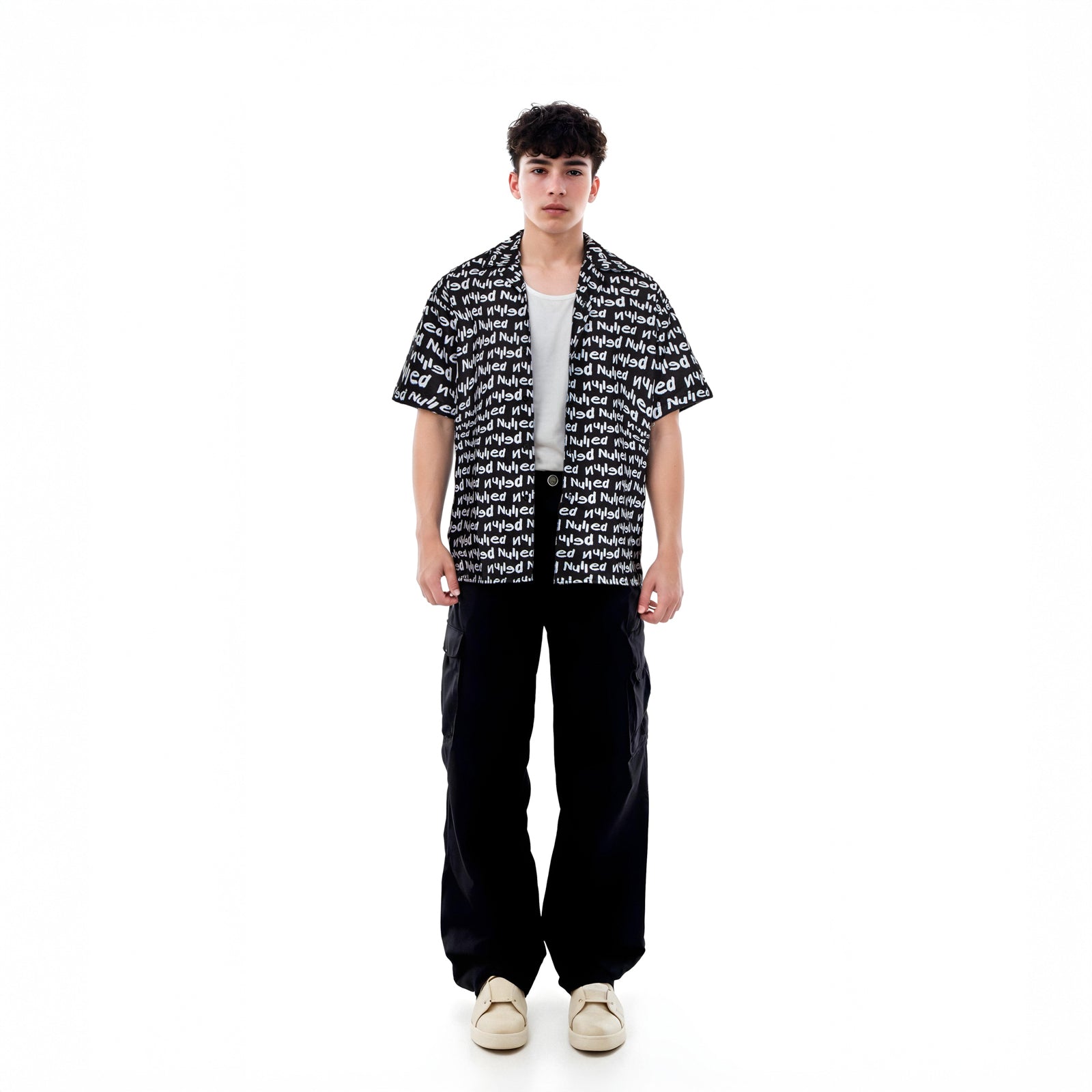 Person wearing a black and white patterned shirt with black pants on a white background