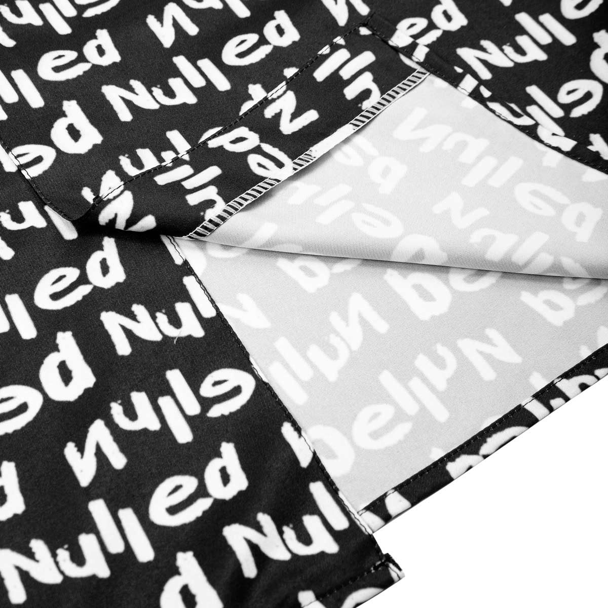 Black fabric with white text pattern, folded over a clear plastic sheet.