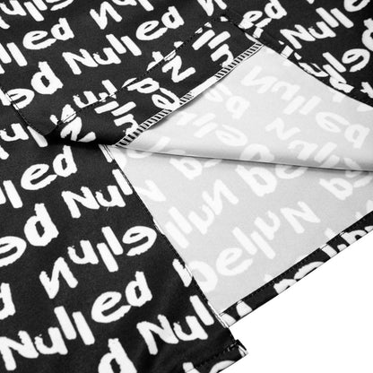 Black fabric with white text pattern, folded over a clear plastic sheet.