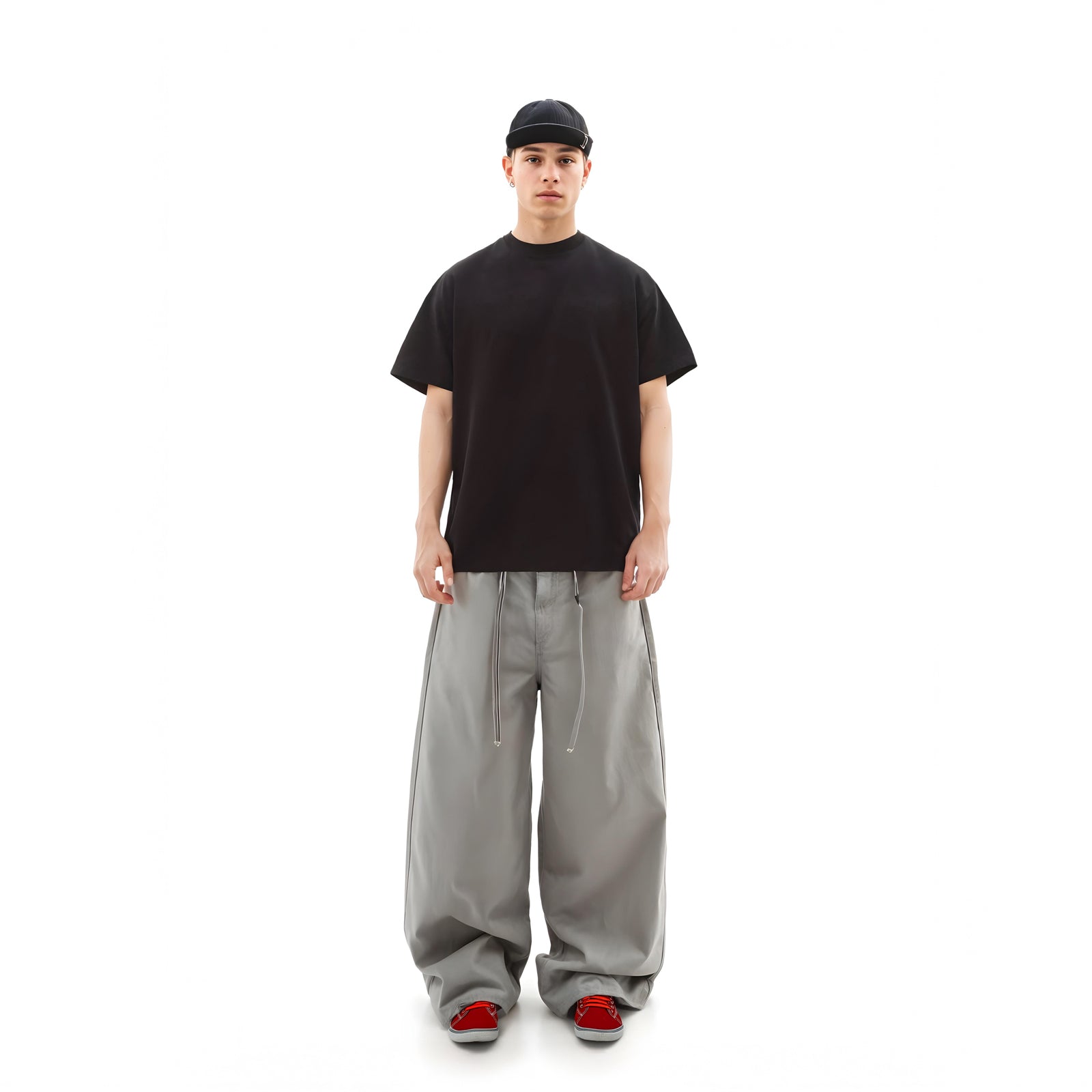 Person wearing a black t-shirt, gray pants, and red shoes on a white background
